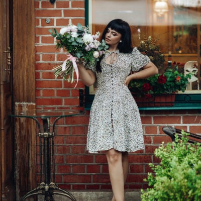 Fashion model with flowers. standing on step of a restaurant.
