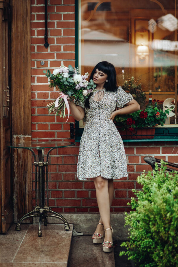 Fashion model with flowers. standing on step of a restaurant.