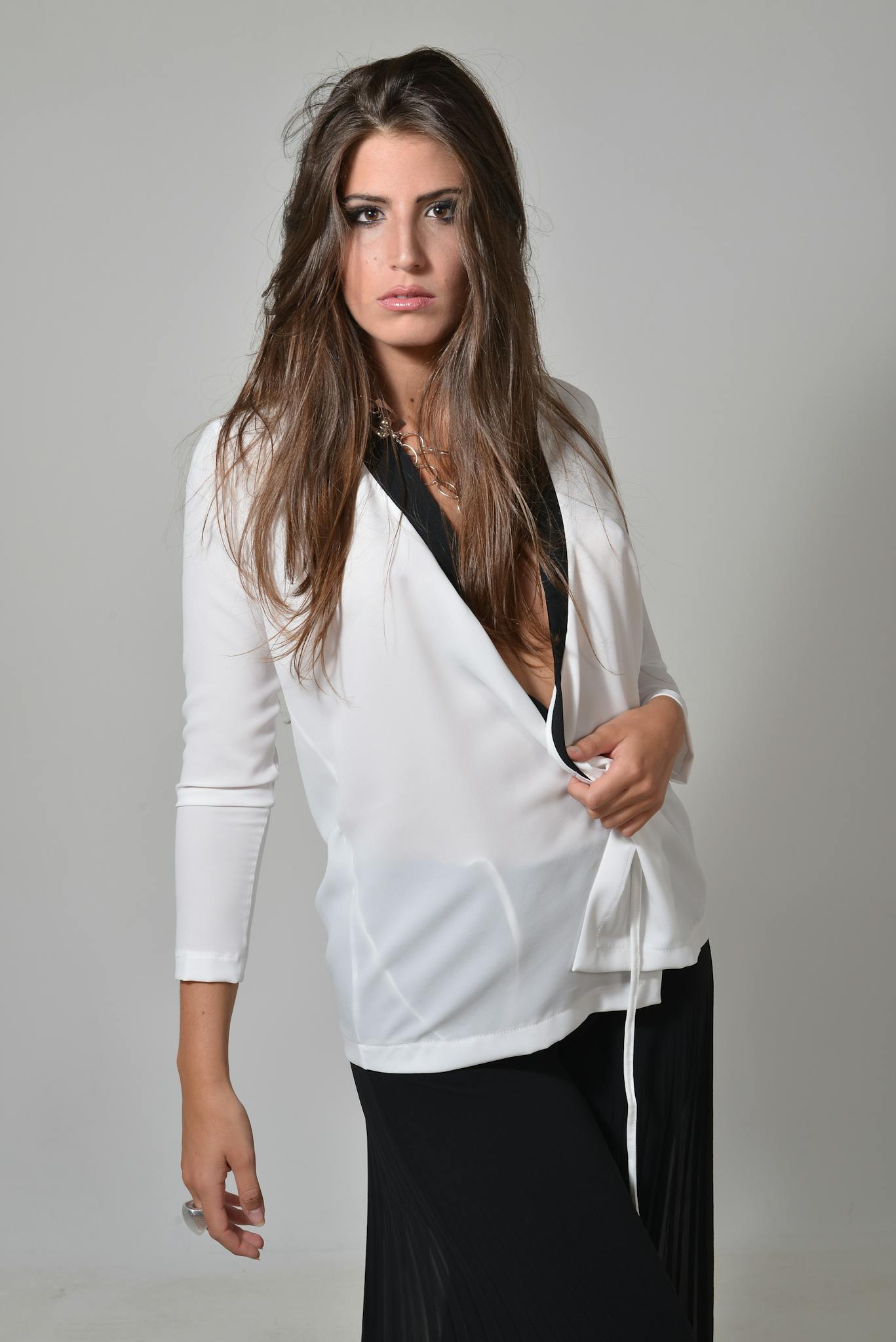 Fashion portrait of a woman in a white blouse and black skirt.