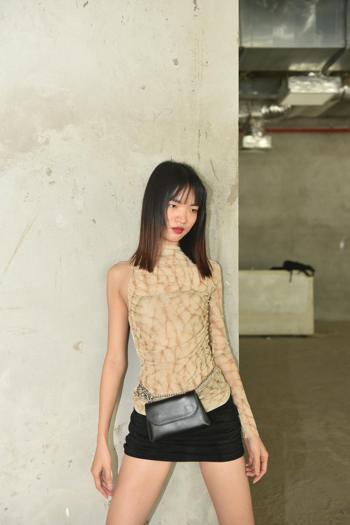 Stylish fashion portrait featuring a model in a black skirt and unique blouse, showcasing modern urban style.