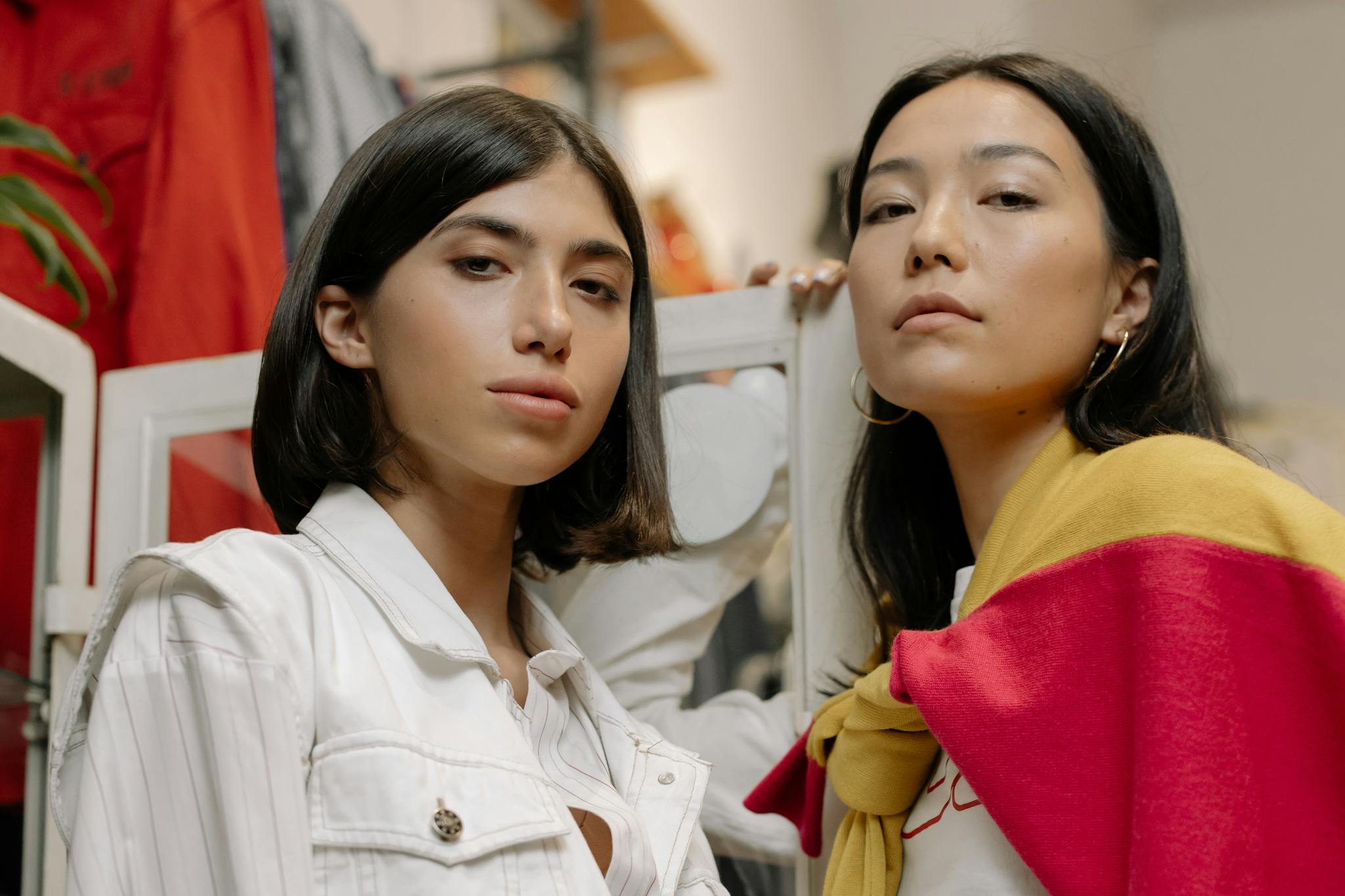 Two fashionable women posing confidently in a trendy indoor boutique environment.